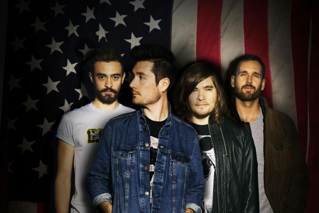 Bastille band members Dan Smith Kyle Simmons Will Farquarson Chris Wood with flag backdrop wallpaper