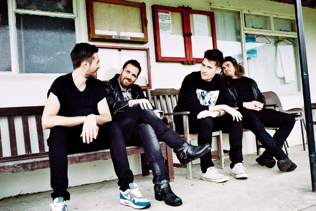Bastille band members Dan Smith Kyle Simmons Will Farquarson and Chris Wood sitting on bench Wallpaper