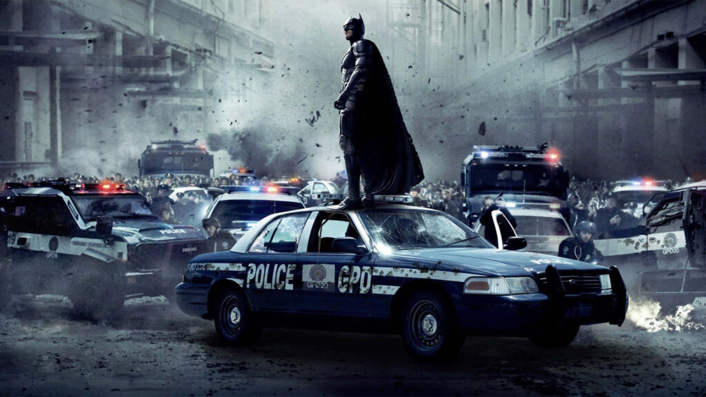 Batman Heroically Overlooks City Chaos: Gritty Urban Wallpaper