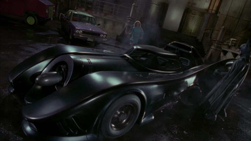 Batman's Iconic Encounter: The Batmobile Takes Center Stage in Gotham's Streets Wallpaper
