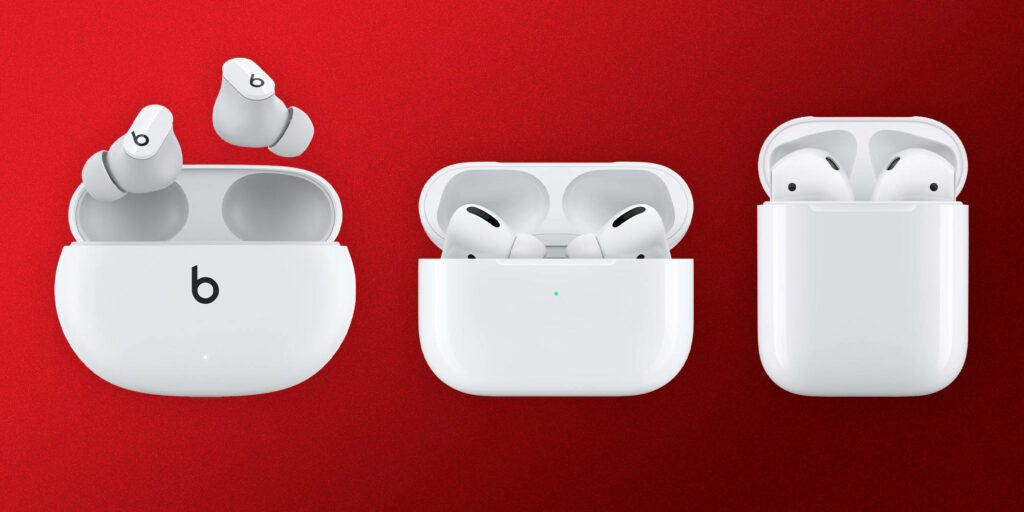 Beats Buds and Apple AirPods wireless earbuds in charging cases on vibrant red background wallpaper