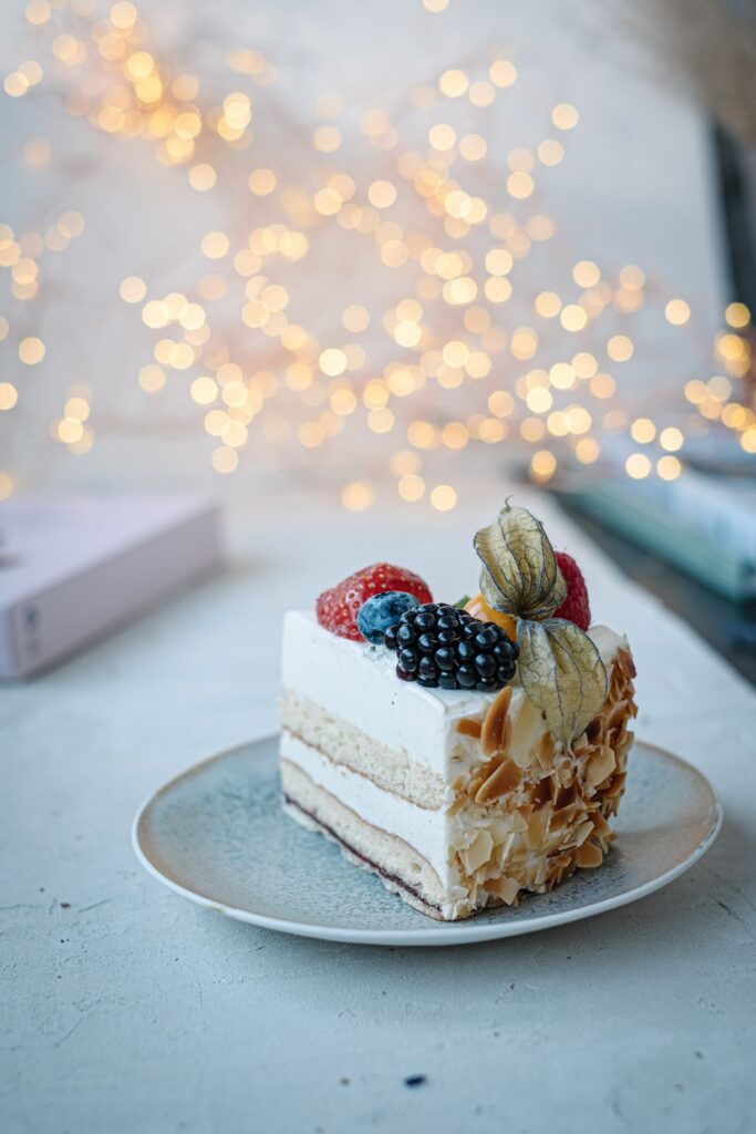 Elegant Cake Slice with Berries: Softly Lit Wallpaper Background
