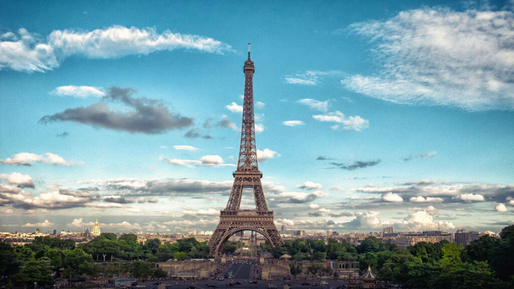 Eiffel Tower Wallpaper: Lush Greenery & Cloudy Sky Background