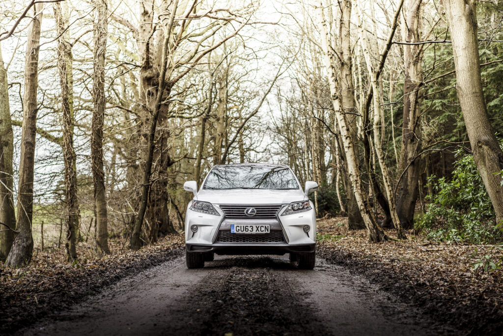 White Lexus RX 450h F-Sport: Elegant Front View in Rustic Setting Wallpaper