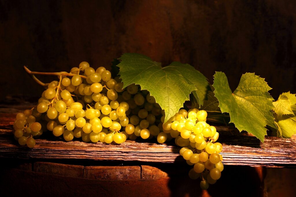 Artistic Wallpaper: Ripe Grapes on Rustic Wood with Green Leaves