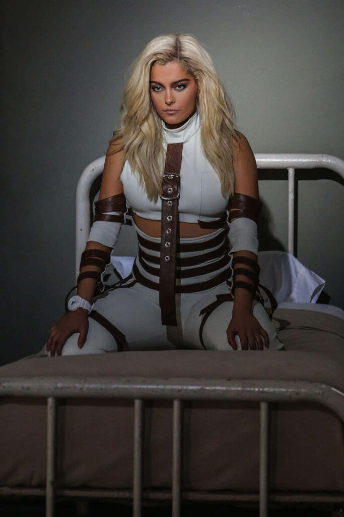Bebe Rexha: Bold Pose in Unique Outfit with Dramatic Wallpaper