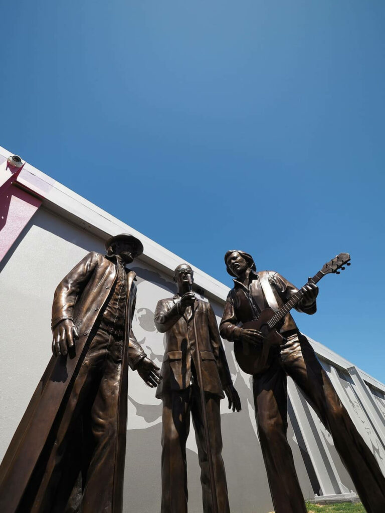 Bronze statue of Bee Gees Barry Robin and Maurice Gibb in Redcliffe Australia under blue sky Wallpaper