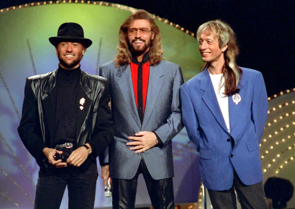 Bee Gees wallpaper showing Barry Robin and Maurice Gibb on stage with vibrant classic backdrop