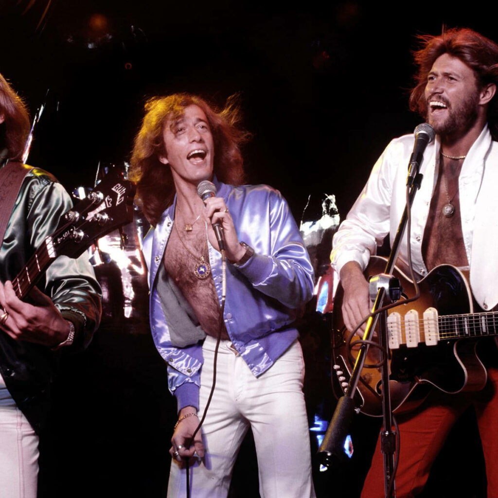 Bee Gees Barry Robin Maurice Gibb energetic live performance vibrant pop band wallpaper background