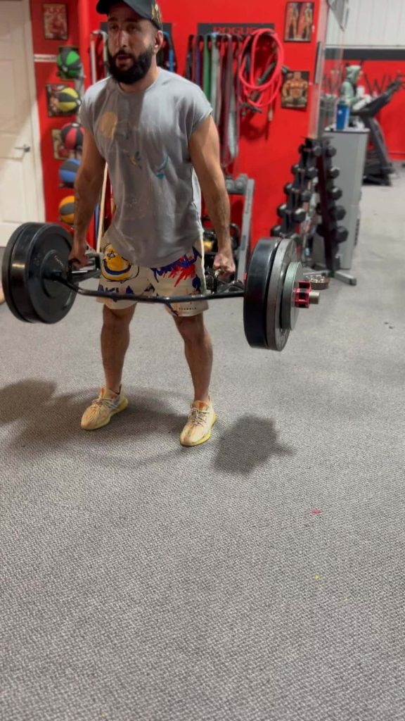 UFC fighter Belal Muhammad performing heavy trap bar deadlift in professional gym with red walls Wallpaper