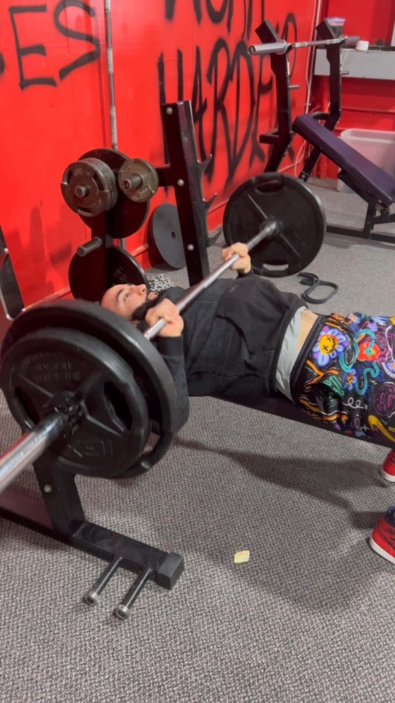UFC welterweight Belal Muhammad lifts barbell bench press in gym with red graffiti wall background Wallpaper