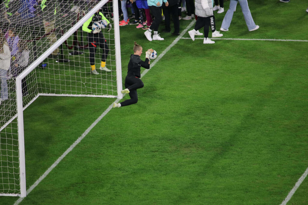 Bella Bixby goalkeeper making a crucial save in intense soccer match with fans watching closely Wallpaper