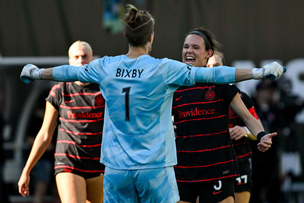 Bella Bixby celebrates with teammates on vibrant soccer field showing team unity and energy Wallpaper