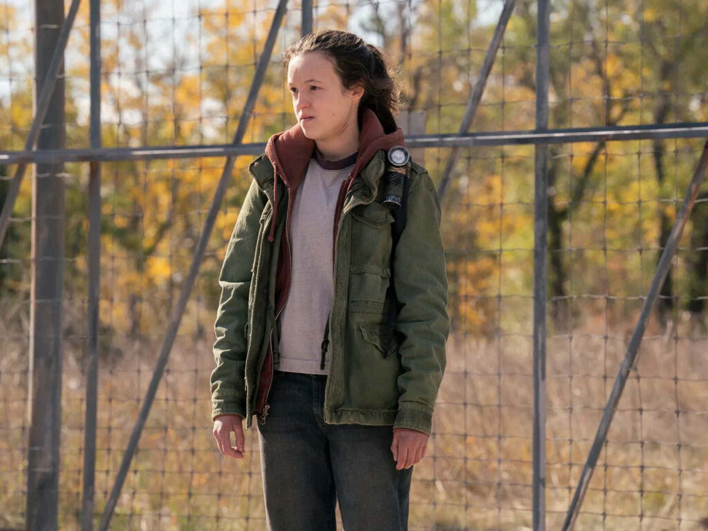 Bella Ramsey in casual rugged clothes outdoors with autumn leaves and wire fence background wallpaper