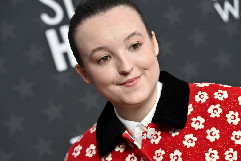 Bella Ramsey close-up portrait wearing red floral jacket at stylish event wallpaper background
