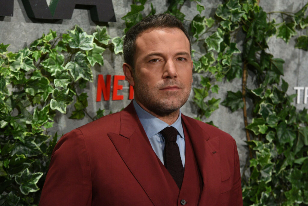 Stylish Ben Affleck in Red Suit - Elegant Greenery Wallpaper Background