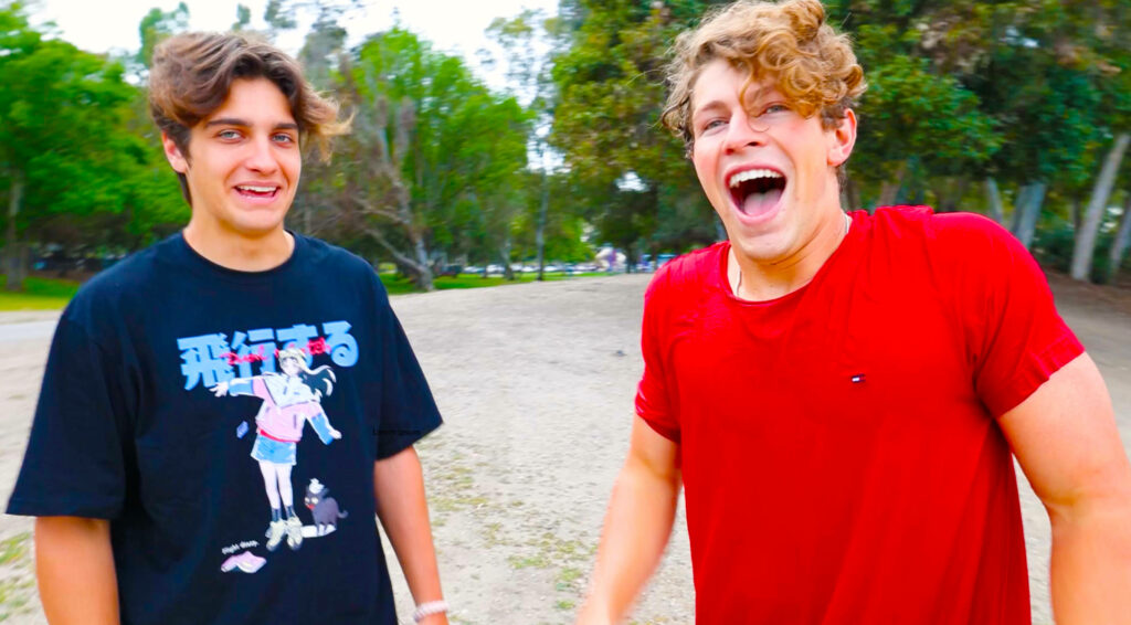 Ben Azelart and Brent Rivera laughing outdoors surrounded by lush greenery wallpaper background