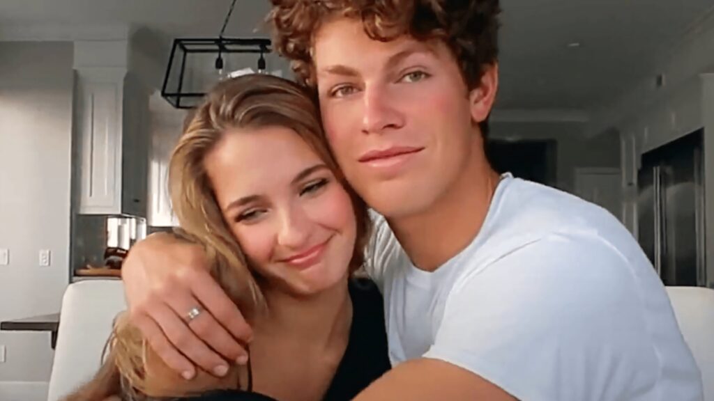 Ben Azelart and Lexi Rivera smiling and hugging in a cozy well-lit room with wallpaper background