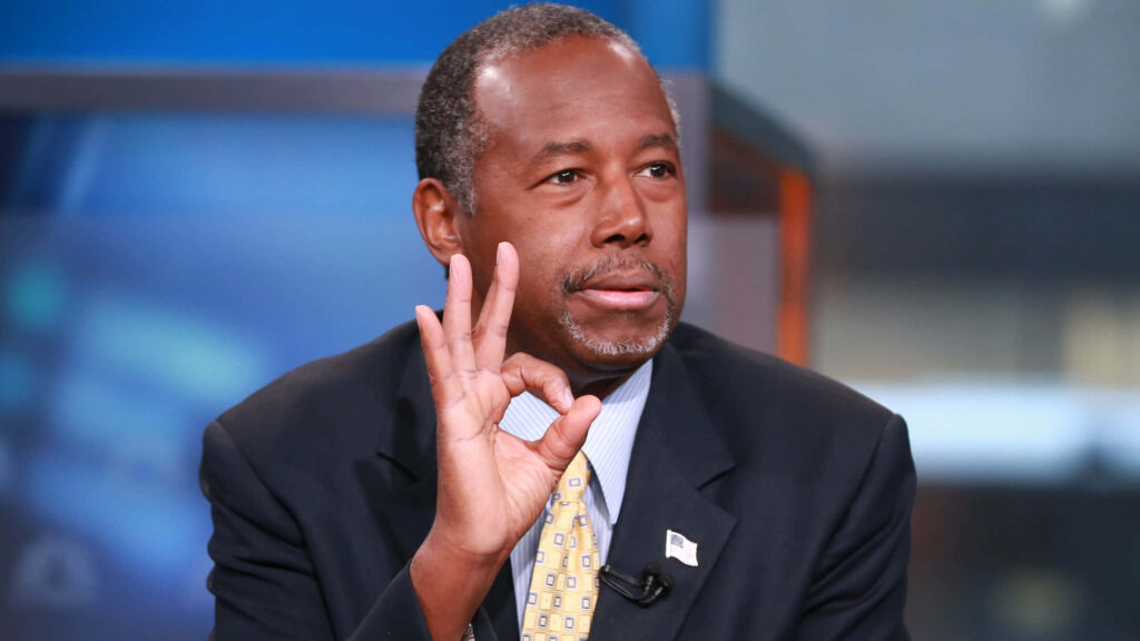 Ben Carson in suit making okay hand gesture confident professional background wallpaper