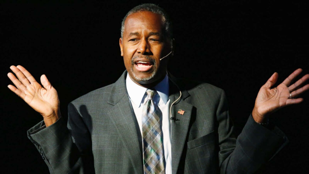 Ben Carson speaking confidently with gestures inspiring leadership against dark background wallpaper
