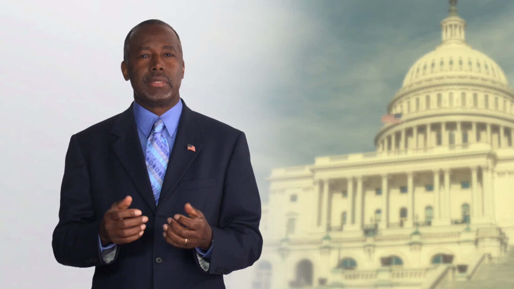 Ben Carson confidently in front of softly blurred United States Capitol patriotic wallpaper background