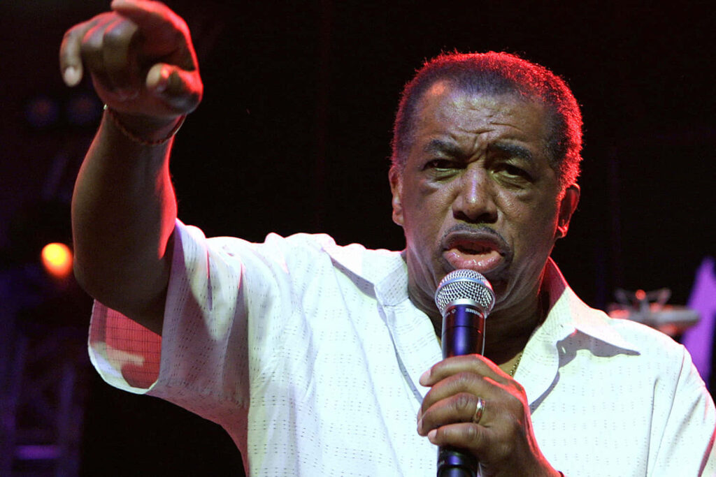 Ben E King singing passionately on stage with microphone soulful music wallpaper background