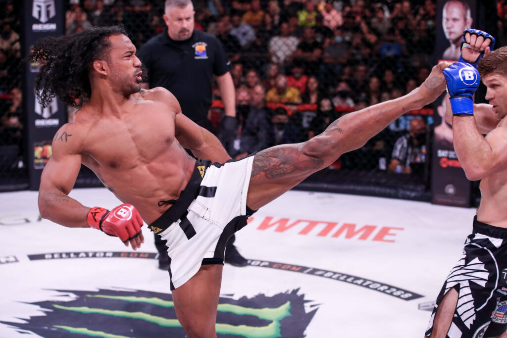 American MMA fighter Ben Henderson performing powerful roundhouse kick in intense cage match Wallpaper