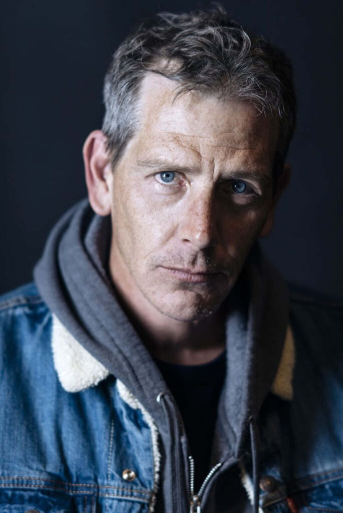 Ben Mendelsohn portrait wallpaper intense blue eyes rugged expression dark minimal background