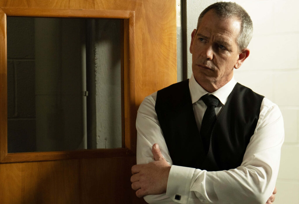 Ben Mendelsohn intense pose in dim hallway dramatic scene wallpaper background