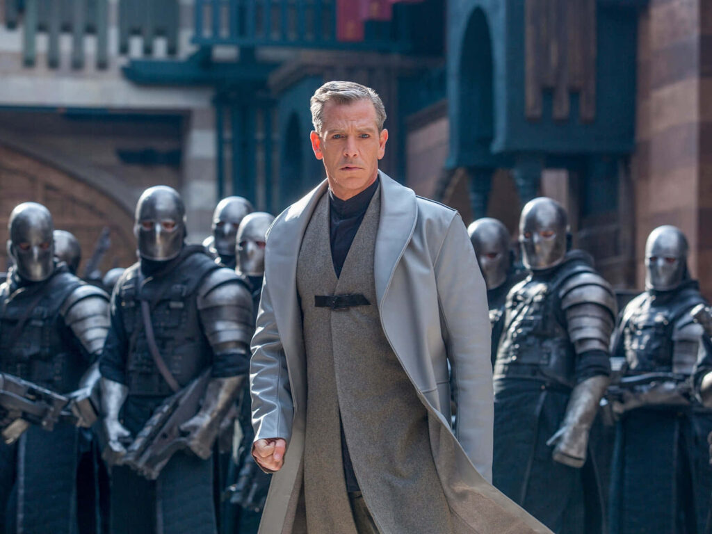 Ben Mendelsohn leading armored troops with commanding presence in striking wallpaper background
