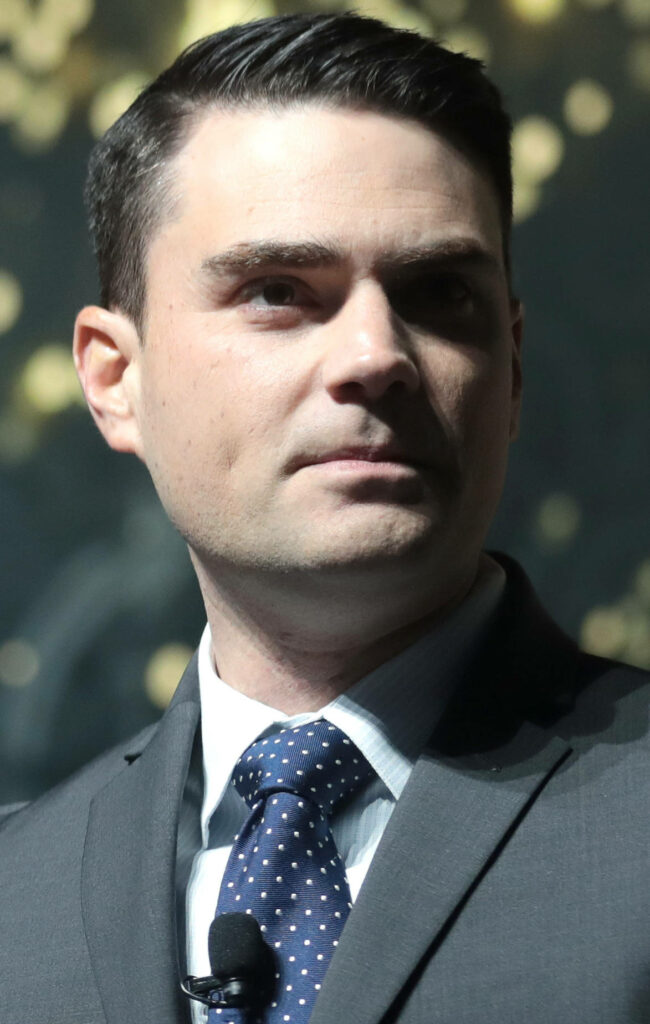Ben Shapiro in formal suit and tie serious expression softly lit background wallpaper