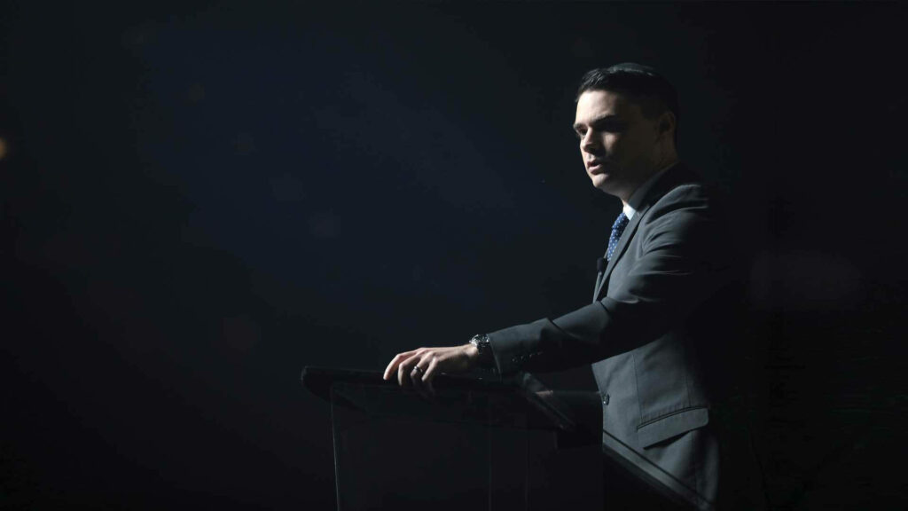 Ben Shapiro speaking at podium in suit with dramatic lighting conservative political commentator Wallpaper