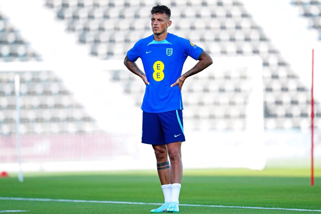 Ben White in blue England training kit standing confidently on football field with stadium background Wallpaper