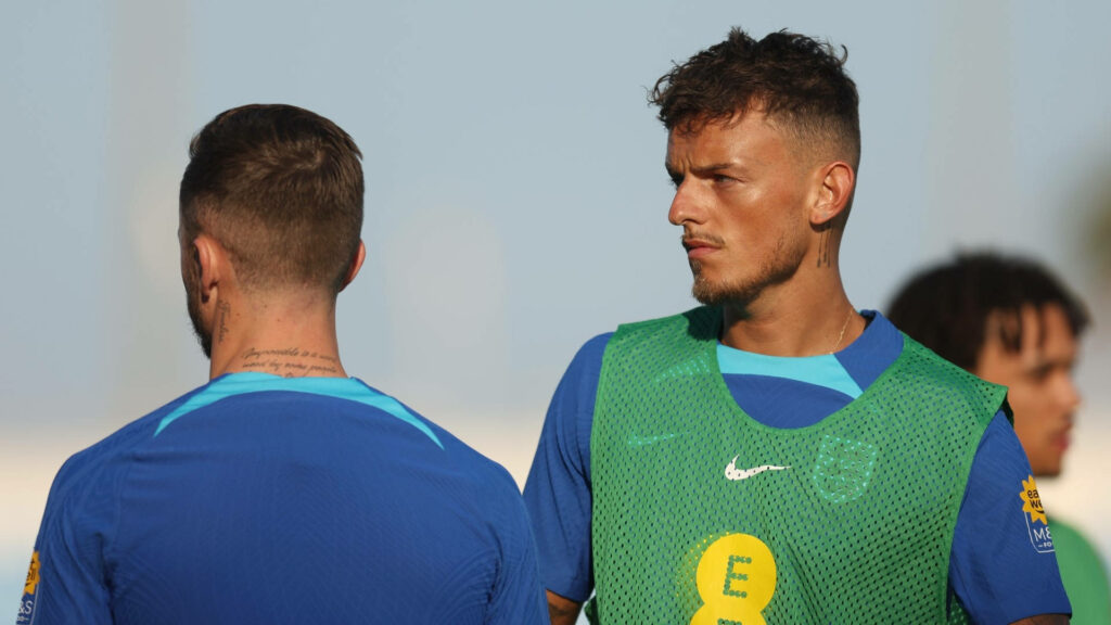 Ben White focused during football training wearing green vest over blue kit with wallpaper background