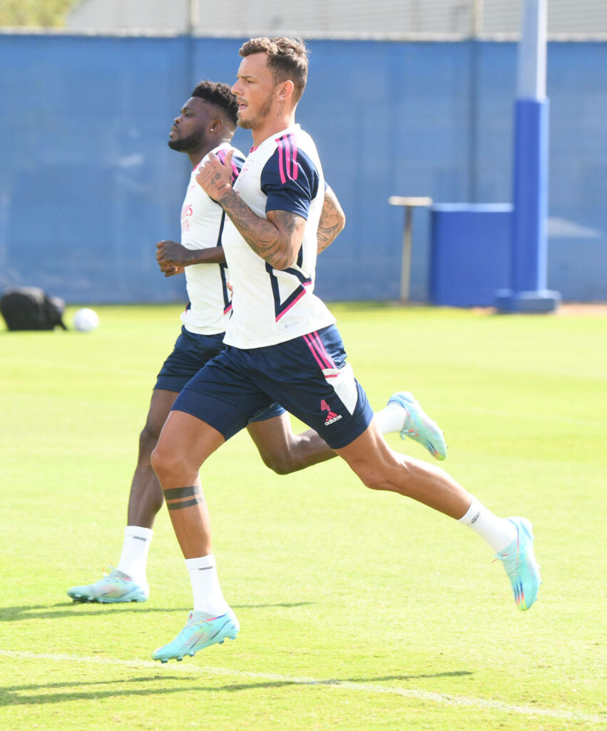 Ben White running intensely during training on vibrant green field showing athletic focus Wallpaper