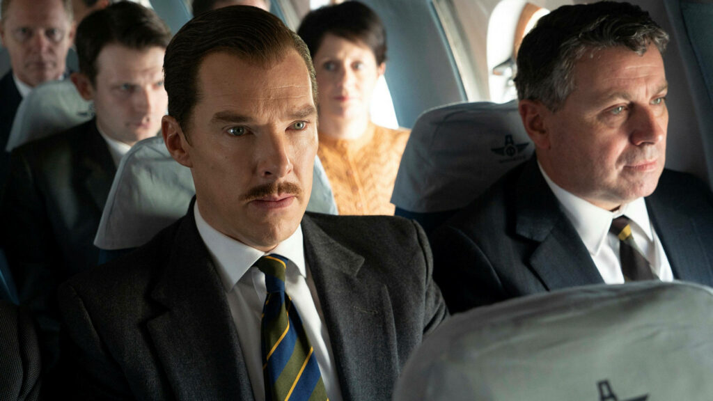 Benedict Cumberbatch in suit and tie seated on airplane surrounded by passengers dramatic scene Wallpaper