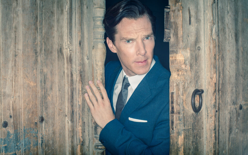 Benedict Cumberbatch in blue suit by rustic wooden door striking sophisticated wallpaper background