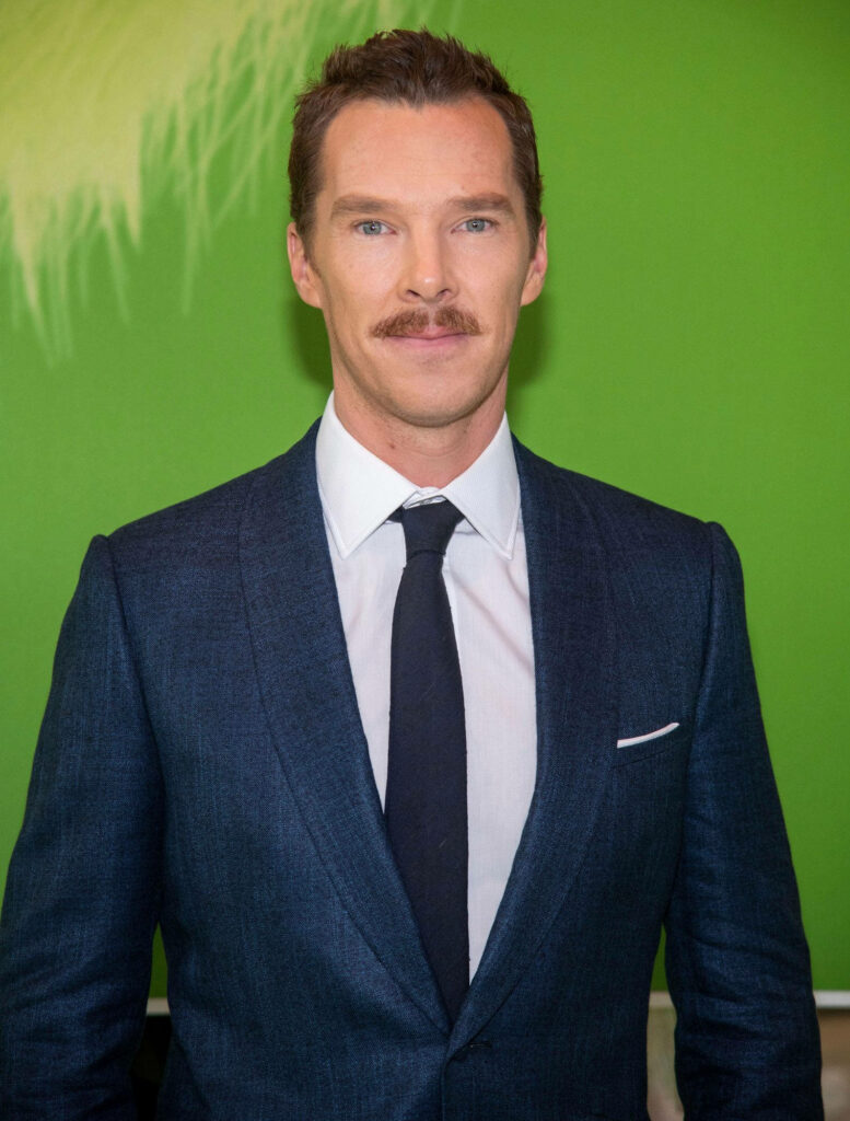 Benedict Cumberbatch in sharp blue suit and stylish mustache vibrant green wallpaper background