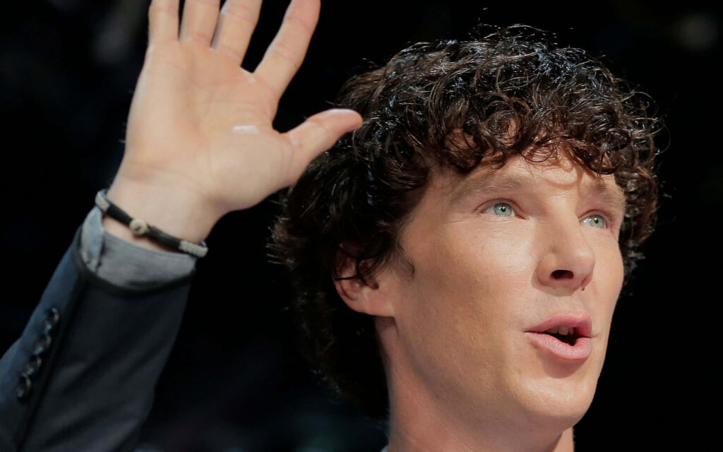 Benedict Cumberbatch close-up with raised hand expressive face signature curls dark wallpaper