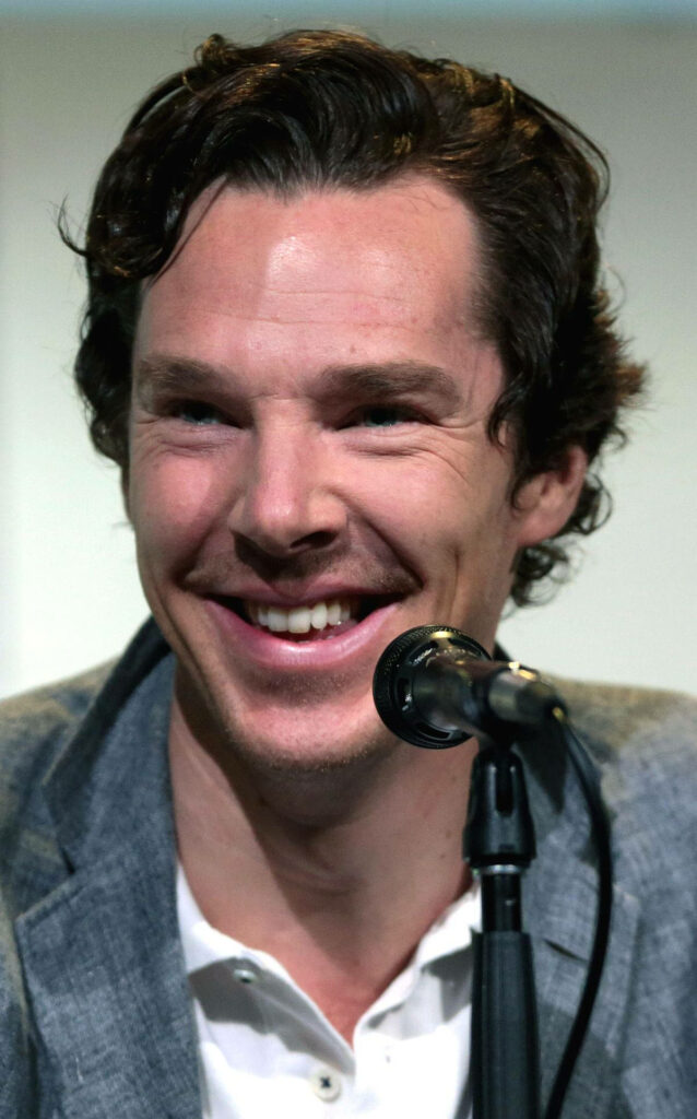 Benedict Cumberbatch smiling in light grey blazer during interview with microphone background Wallpaper