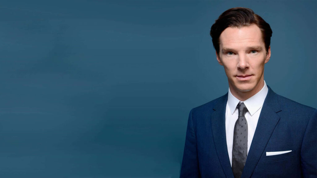 Benedict Cumberbatch in sharp blue suit and patterned tie against plain blue background wallpaper