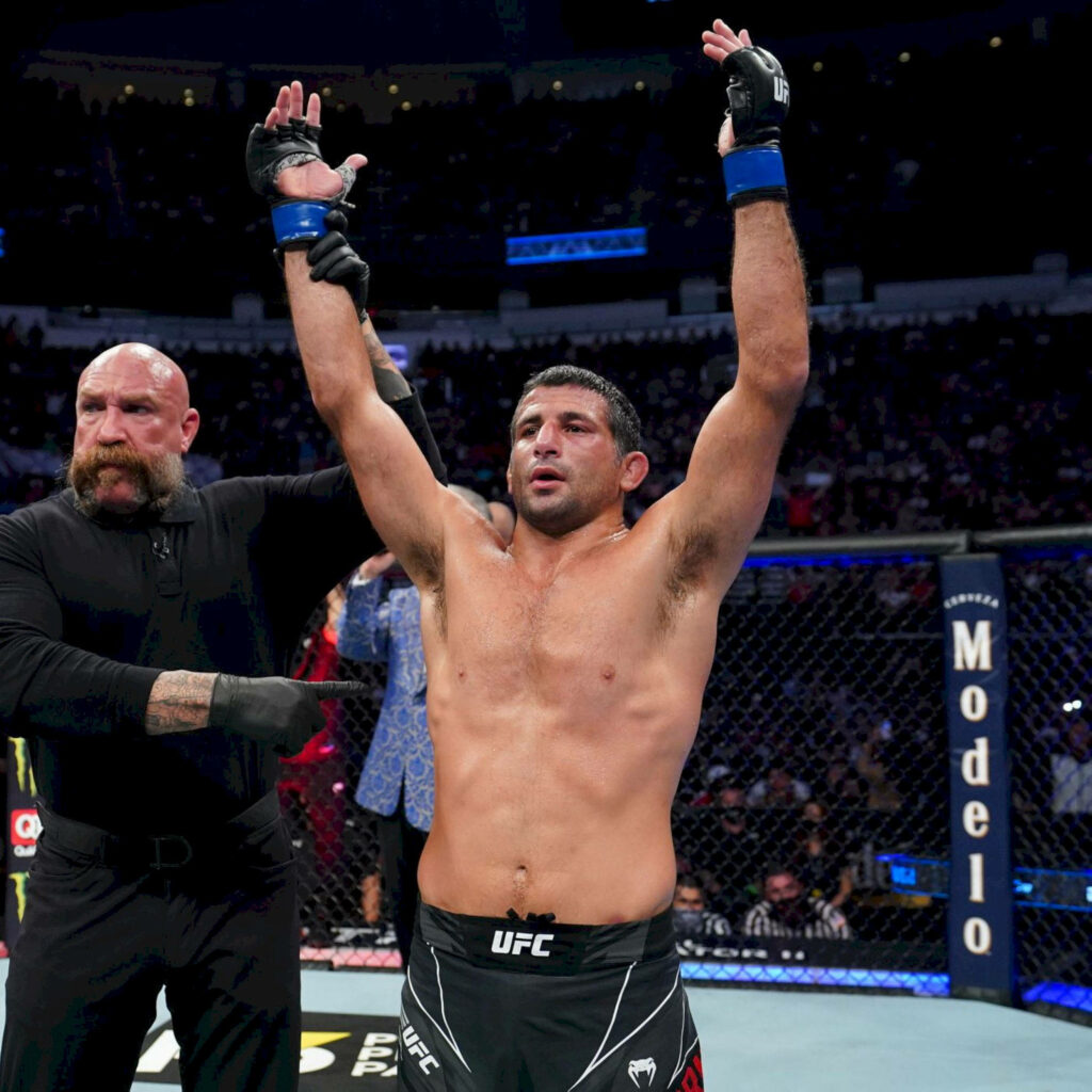 Beneil Dariush celebrates UFC victory raising arms inside octagon with crowd and officials background Wallpaper