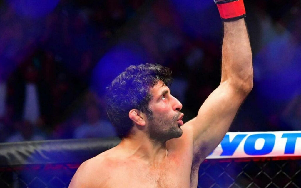 Beneil Dariush celebrates MMA victory raising left arm inside cage showing determination Wallpaper