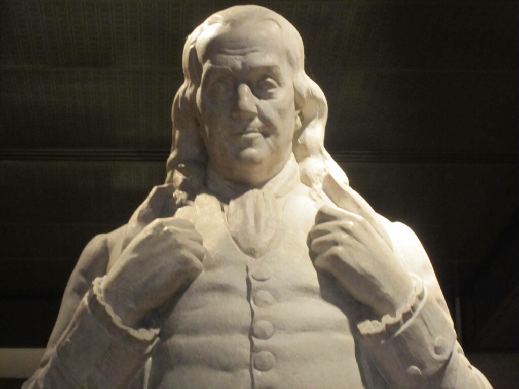 Marble statue of Benjamin Franklin with detailed features on elegant wallpaper background