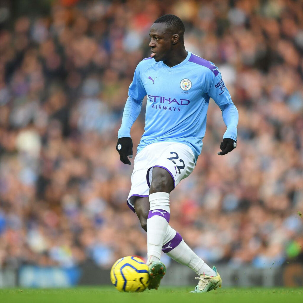 Benjamin Mendy focused on ball playing football on lush green field during match wallpaper background