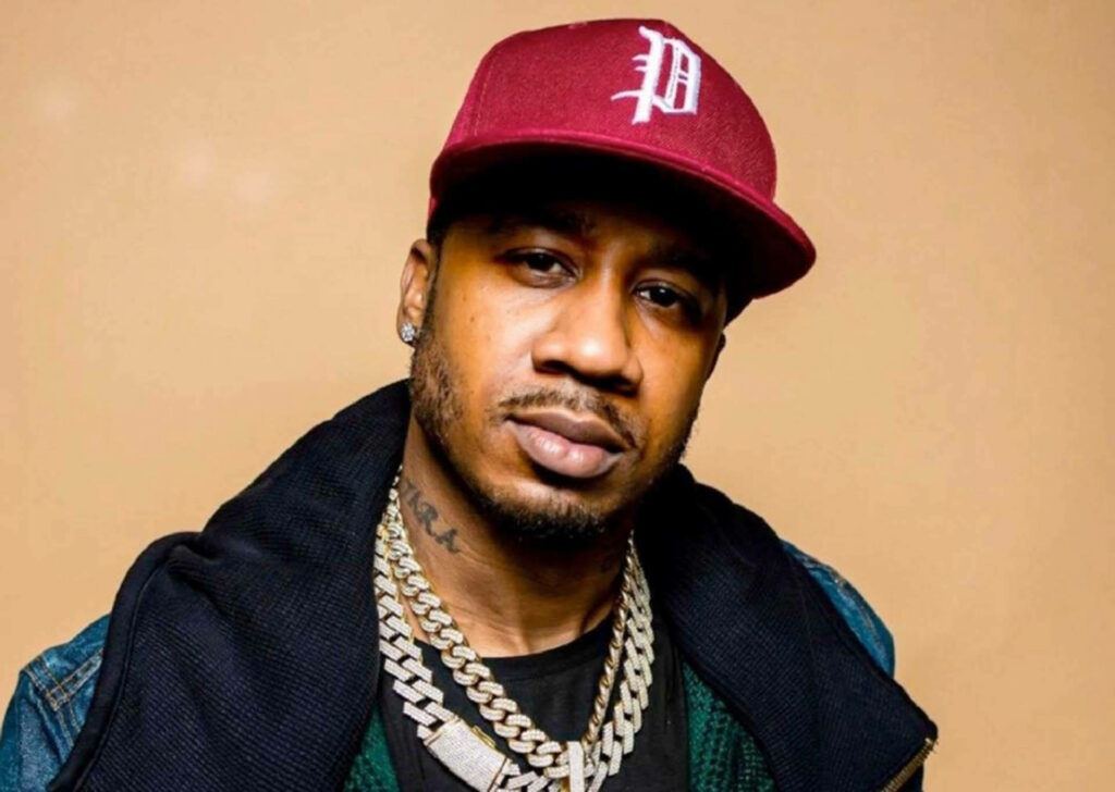 Benny The Butcher in maroon cap and layered chains confident pose wallpaper background