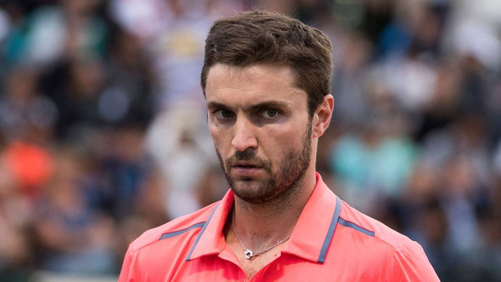 Close-up of tennis star Benoît Paire in pink polo with intense focused gaze at stadium crowd Wallpaper