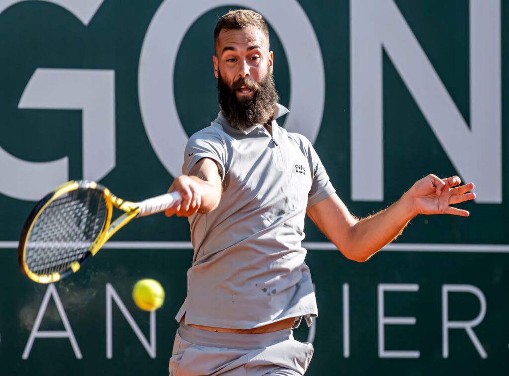 Benoît Paire focused preparing powerful tennis shot during match on vibrant wallpaper background