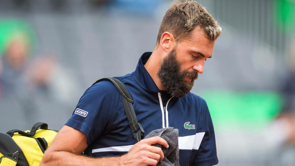 Benoît Paire in athletic gear with backpack looking down thoughtfully in reflective wallpaper