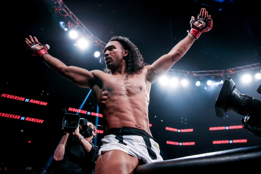 Benson Henderson triumphant in MMA cage celebrating victory showing athleticism and confidence Wallpaper
